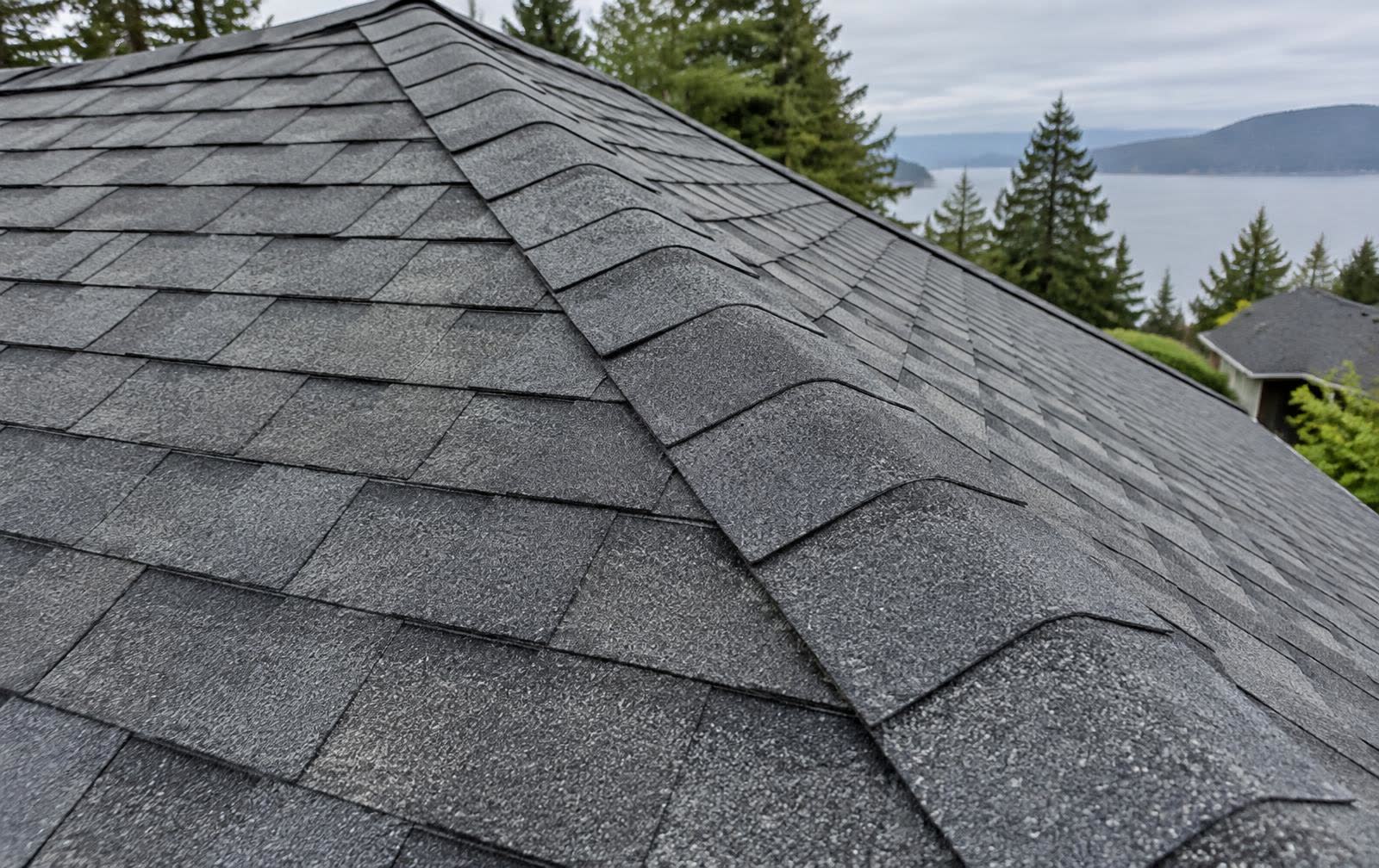 Close-up aerial view of new asphalt shingle rows and a roof ridge line
